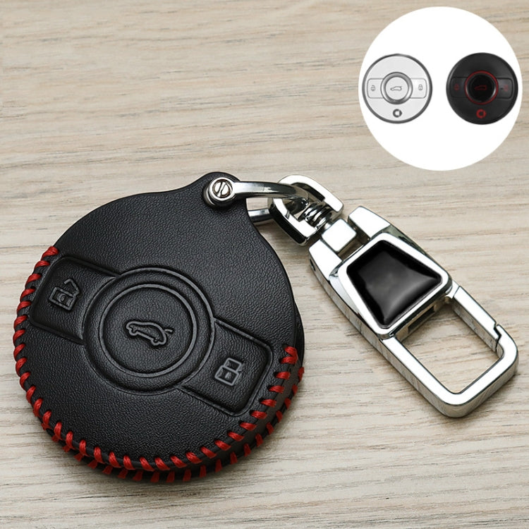 Black leather key fob cover with round button panel, red stitching, and chrome buckle