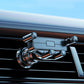 Car air vent phone holder showing clamp arms and extension pole, dark metal finish