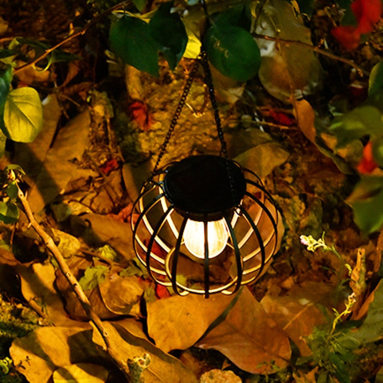 Lit small black metal solar lantern light with hanging chain and clear bulb