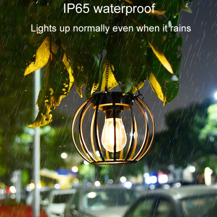 Lit small black metal solar lantern light under rain, hanging chain visible