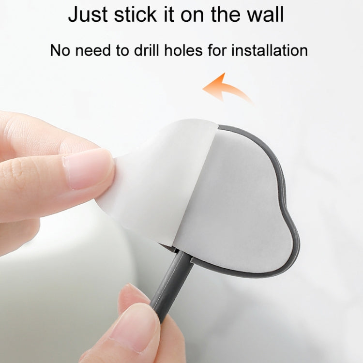 Adhesive wall hook with backing being peeled off, showing the mounting pad