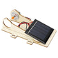 Solar powered wooden car kit with installed solar panel, motor, and connected red wires