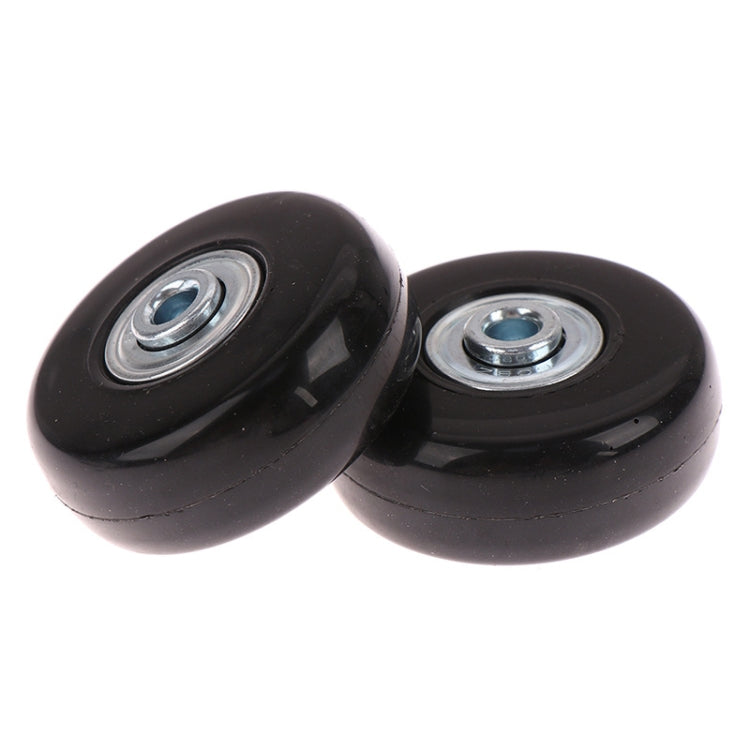 Close-up of two black luggage spinner replacement wheels with visible metal bearings