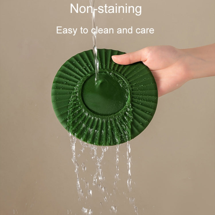 Green silicone heat insulation mat with water dripping onto the ridged surface.