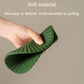Green silicone heat insulation mat shown flexing, ridged outer edge and center.