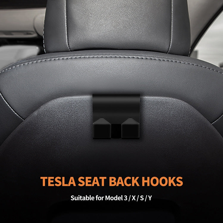 Tesla Model 3/Y close-up of two black plastic rear seat headrest hooks on seat back.