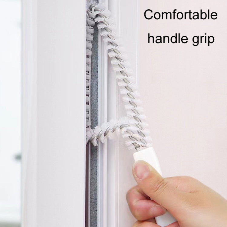 Hand holding a white window crevice brush for cleaning tight frame edges