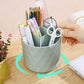 Light green rotating desk organizer bucket holding pens and scissors, hand in frame