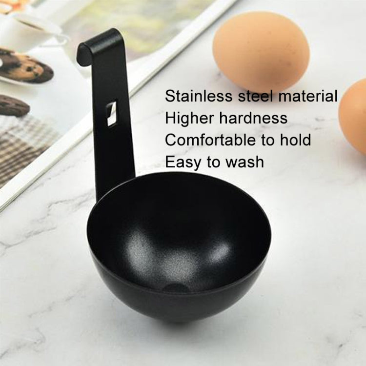 Black egg poaching mould cup with hanging handle, shown near eggs.