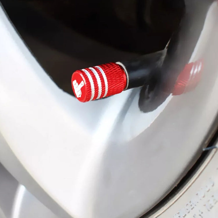 Close-up of a red tire valve cap with knurled texture on a wheel rim