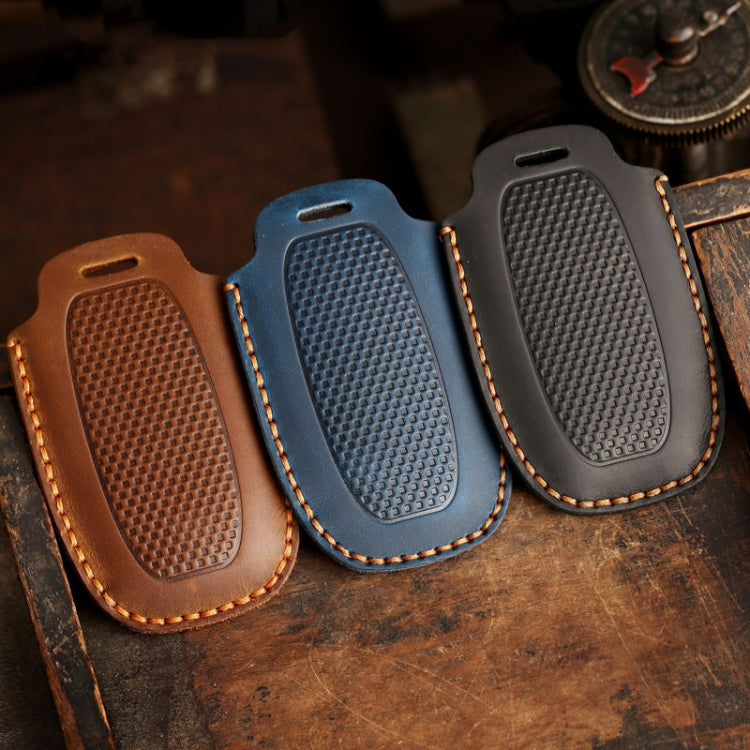 Set of three leather key fob covers in brown, blue, and dark gray with textured grip