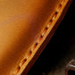 Close-up of tan leather key fob cover seam and burnished edge stitching