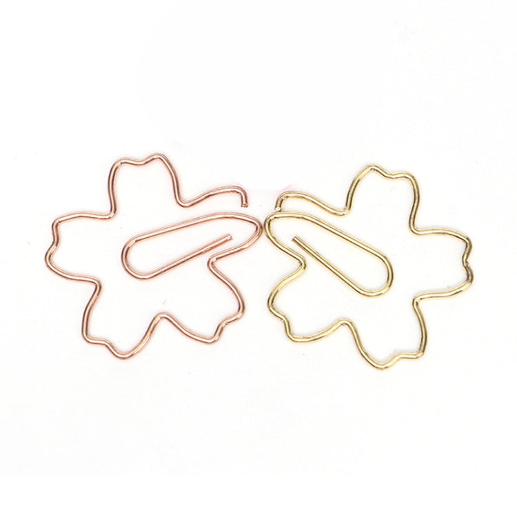 Mixed rose gold and gold sakura-shaped metal paper clips, close-up pair