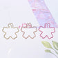 Three sakura-shaped metal paper clips in gold, rose gold, and pink on stationery