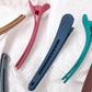 Assorted duckbill bangs clips in pink, navy, teal, and brown colors.