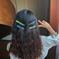 Colorful duckbill bangs clips holding straight bangs on dark hair.