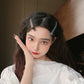 Light gray duckbill hair clip holding side bangs on dark hair.