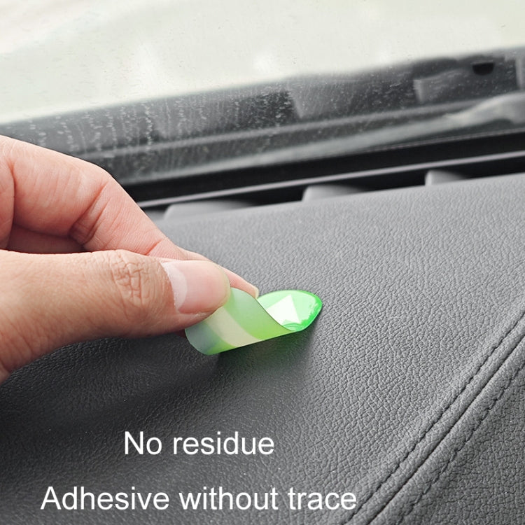 Hand placing a small green luminous up-arrow sticker on car interior surface