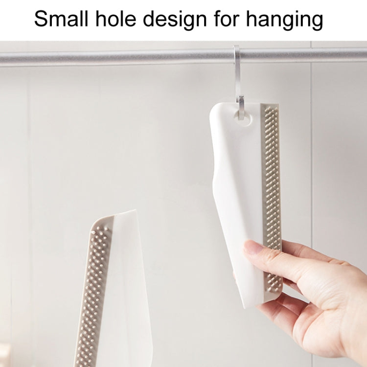 Manual cleaning scraper with hanging hole, held up to show brush head