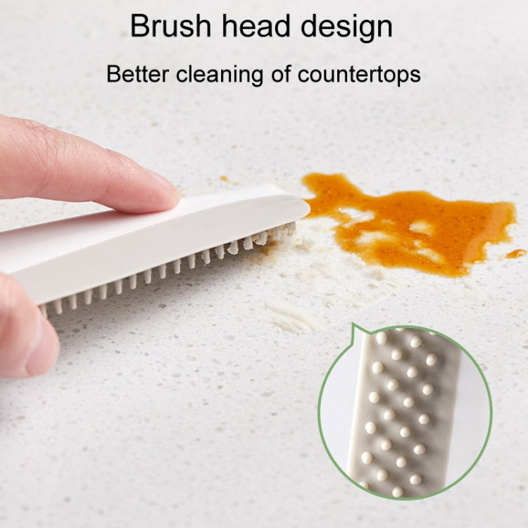 Manual cleaning scraper showing perforated brush head cleaning a stained countertop