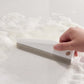 Manual cleaning scraper with perforated brush head wiping foamy sink surface