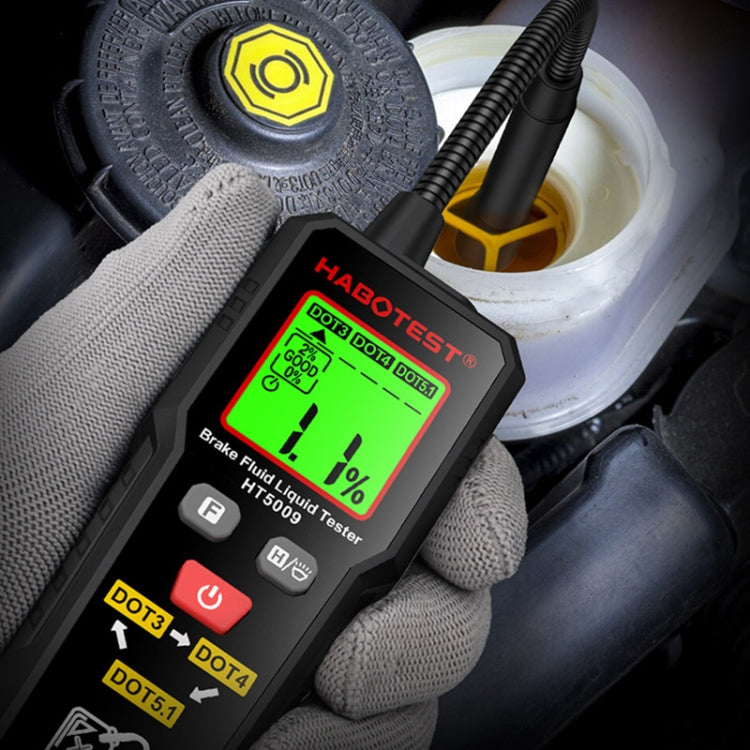 Close-up handheld brake fluid moisture tester showing green screen reading in gloves