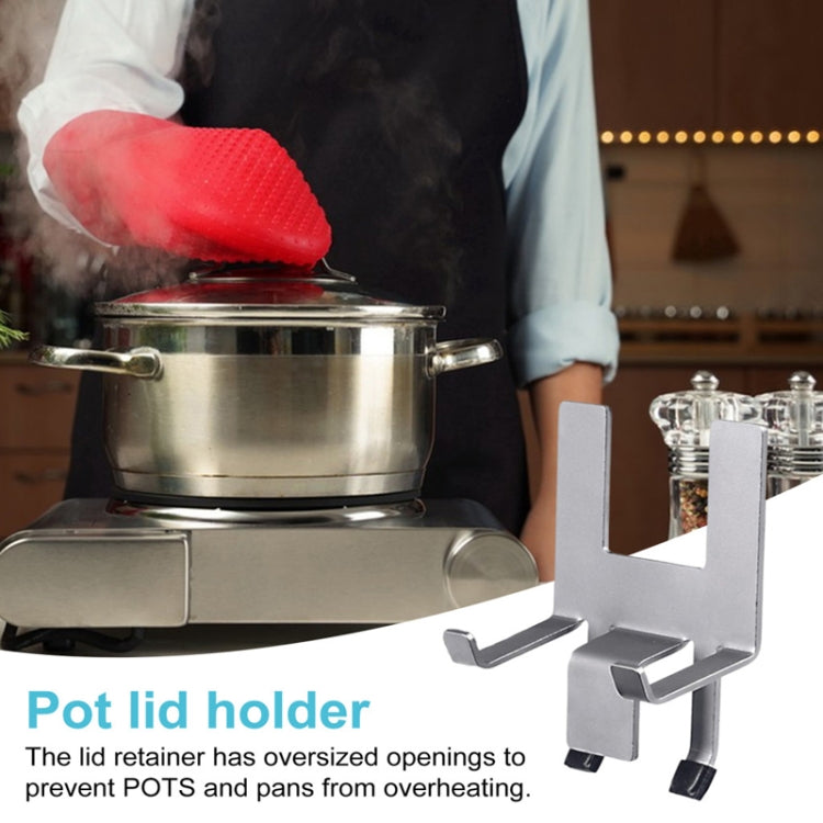 Stainless steel pot lid holder with silicone grip feet on a stovetop pot