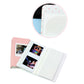 Photo album open with two square photo prints and white pages with dots