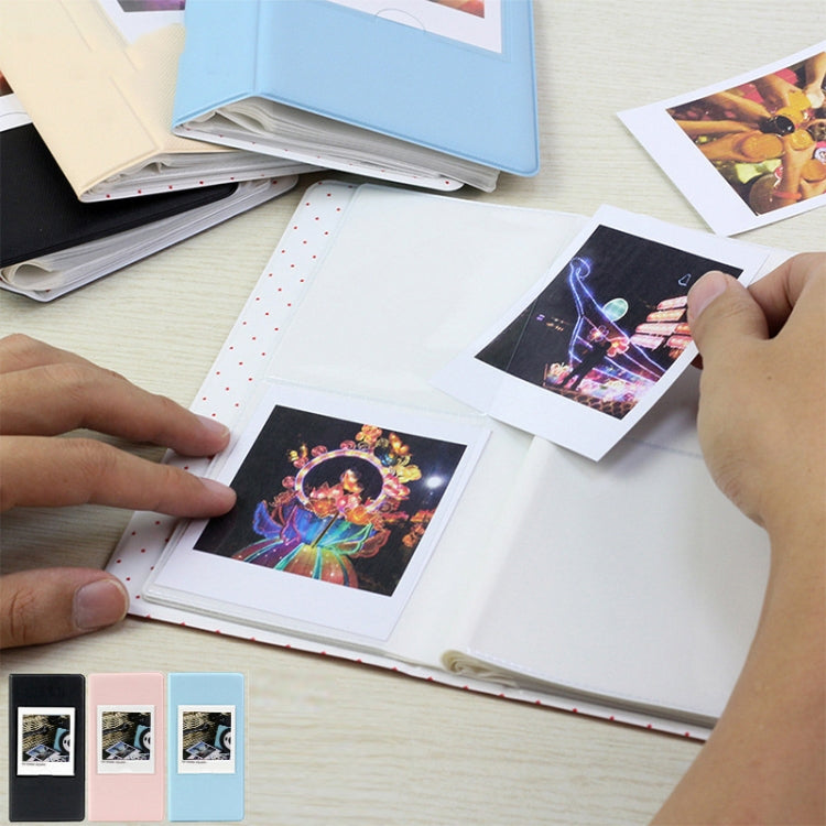 Light blue photo album with square prints being inserted by hands