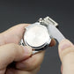 Watch repair tools: hands hold a watch while prying the case back