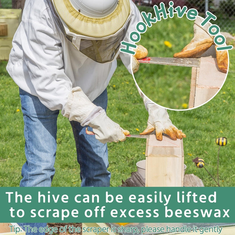 Beekeeper suit with veil and gloves using a wooden-handled hive scraper