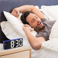 Blue LED alarm clock on bedside table with segmented time display