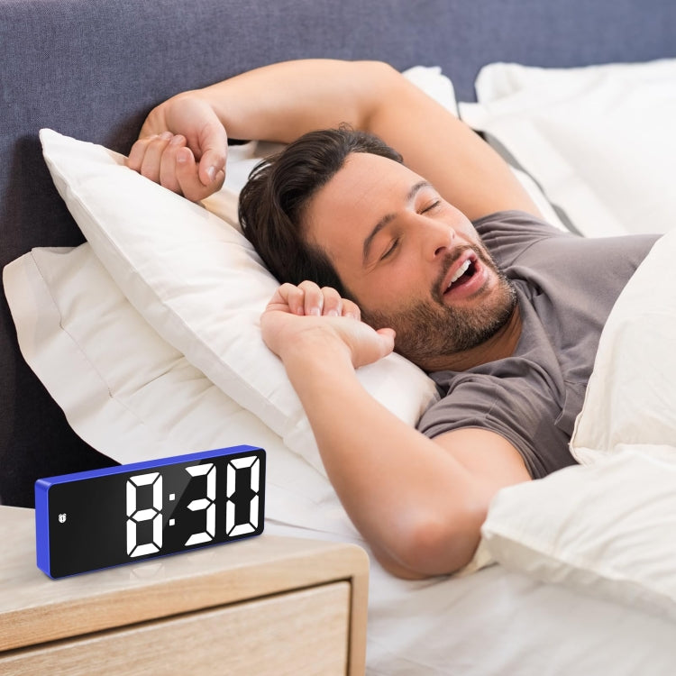 Blue LED alarm clock on bedside table with segmented time display