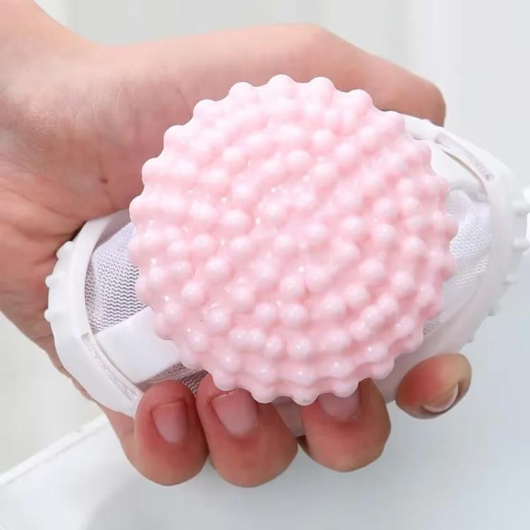Pink studded hair lint catcher ball on a white mesh cone bag, held in hands