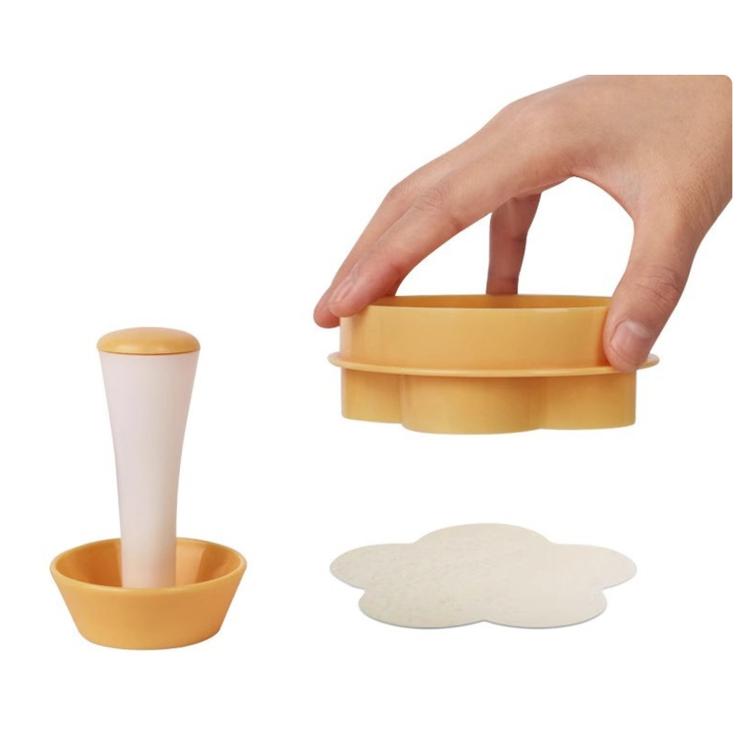Yellow cake cup press mold set with white dough shapes and stacked cup inserts