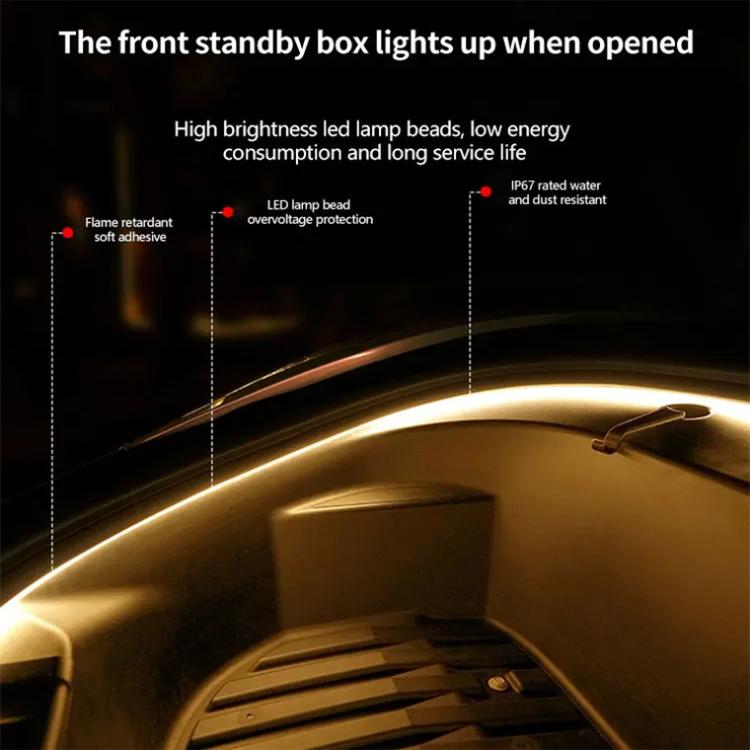 Front trunk interior LED light bar along edge with warm amber illumination