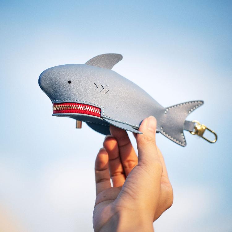 Light blue shark-shaped key cover held in hand, red zipper and gold ring