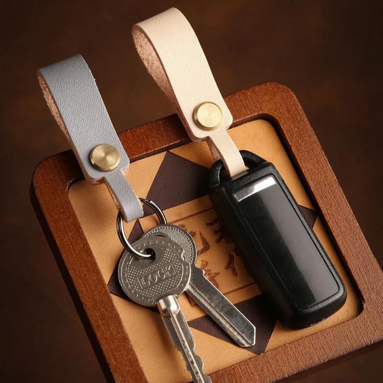 Leather lanyard keychain with brass snap holding keys and a car remote in box.
