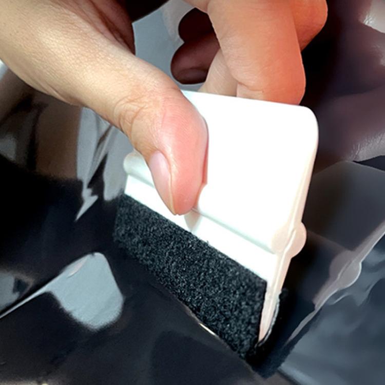 Small anti-scratch scraper with white plastic edge and black felt pad on car film