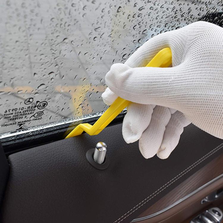 Yellow plastic film edge scraper held in white glove, for tucking window film