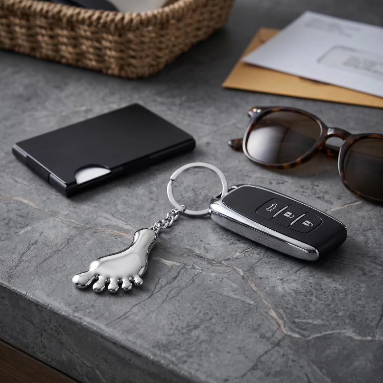 Silver metal foot-shaped keychain charm with round keyring and chain