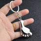 Silver metal foot-shaped keychain charm held in an open hand
