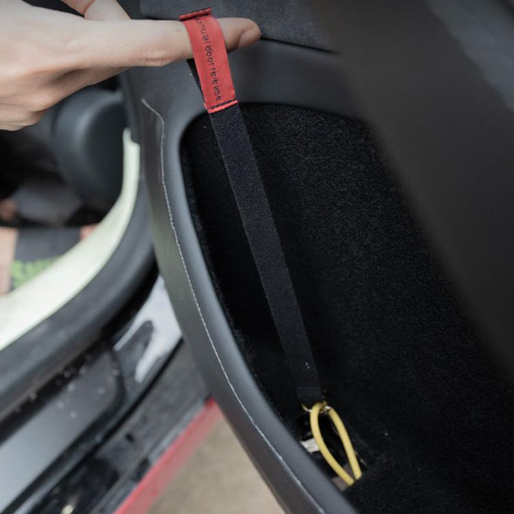 Red manual release pull cord on black door panel trim with metal loop end
