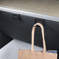 Dark gray glove box hidden hook holding a paper shopping bag