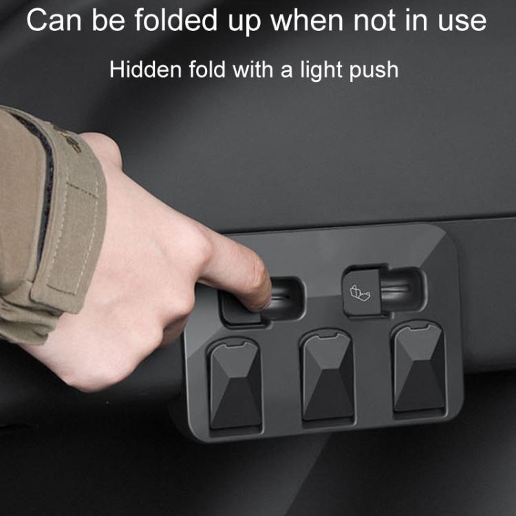 Hand pressing a dark gray trunk folding hook, panel with three fold-out hang points
