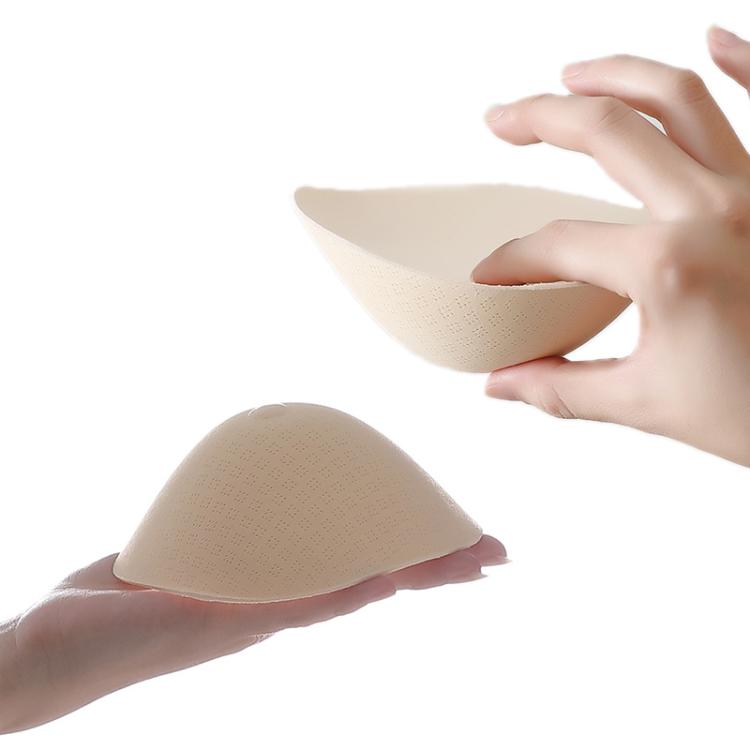 Beige prosthetic breast simulation cups being placed by hands
