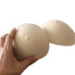 Two beige prosthetic breast pads with textured surface, held by hands