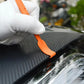 Gloved hand using an orange edge squeegee scraper to apply car film