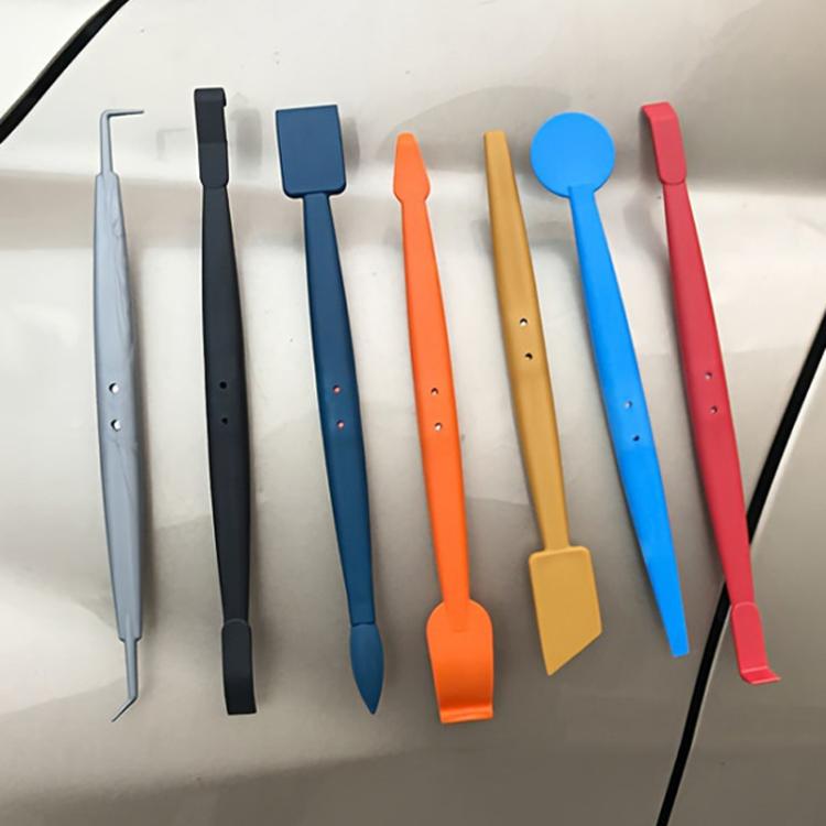 Car wrap trim tools laid out on a surface; assorted colored scraper heads