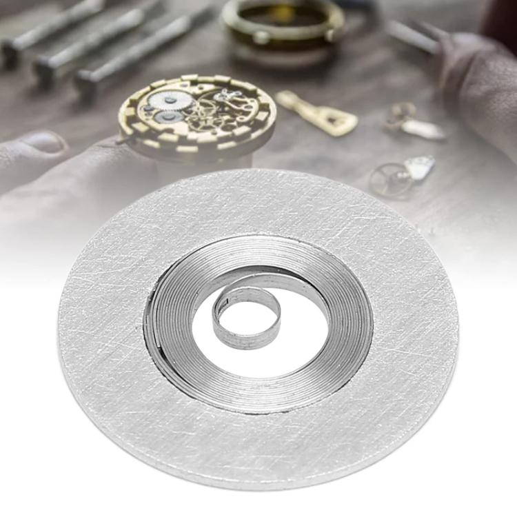 Round metal watch movement winder disc with central ring and spiral grooves